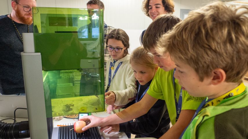 Cla Tschenett (links) von der Grafikfirma Aimara AG in Müstair hat den Kindern soeben gezeigt, wie die Schale eines Apfels mittels Lasertechnik beschriftet werden kann.