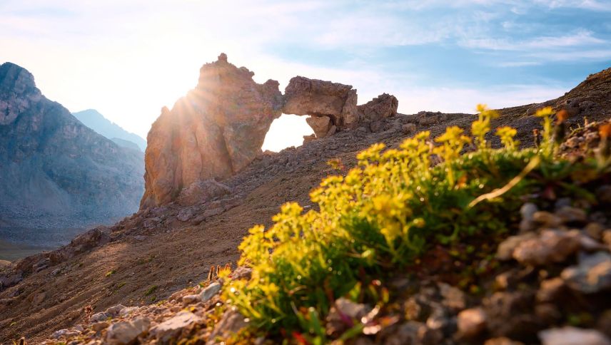 In der Val d’Agnel im Parc Ela, einem Seitental des Julierpasses, leuchtet die tiefstehende Morgensonne durch ein natürliches Felsentor. Erreichbar über den Wanderweg ab Julier-Hospiz. Foto: Graubünden Ferien