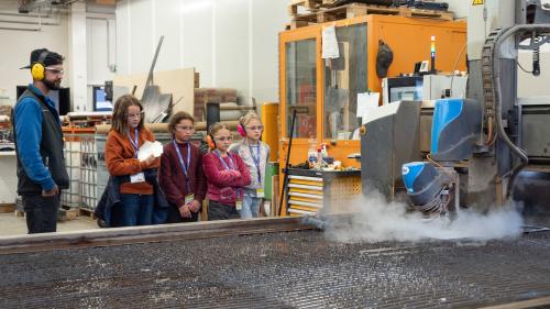 Jon-Corsin Neuhäusler (links) der Tschenett AG beobachtet mit MINT-Schülerinnen gespannt, wie ein Wasserstrahl die zuvor programmierten Dachteile ihres Vogelhäuschens aus einer Aluminiumplatte schneidet. Fotos: Jon Duschletta