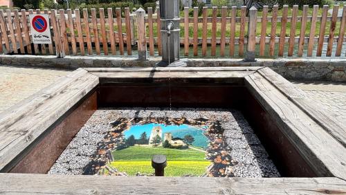 Die Kirche San Gian als Teil einer fotografischen Brunneninstallation. Laura Ceretti rahmt das Celeriner Wahrzeichen mit einem Fries aus Holzstapeln und verbindet so Landschaft, Architektur und Wasser. Foto: Sabrina von Elten