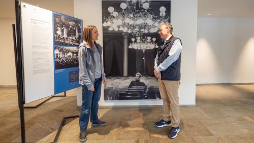 Nina Debrunner und Festivalintendant Jan Schultsz in der Ausstellung des Engadin Festivals. Im Hintergrund Herbert von Karajan im Konzertsaal des Reine Victoria im Jahr 1964. Foto: Jon Duschletta